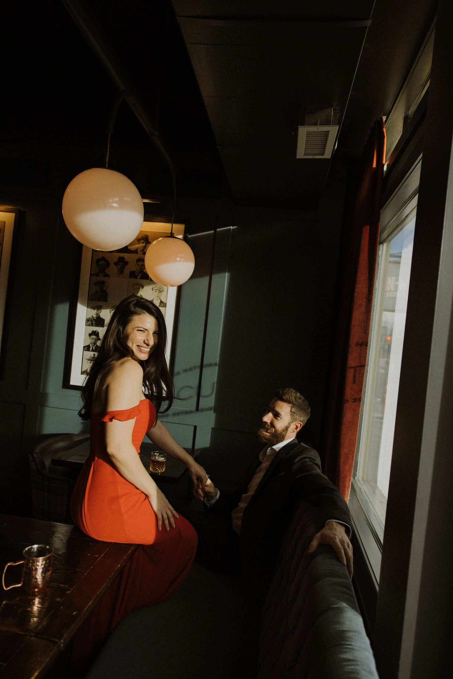 A couple shares an intimate moment in a dimly lit restaurant with glowing paper lanterns and modern decor.