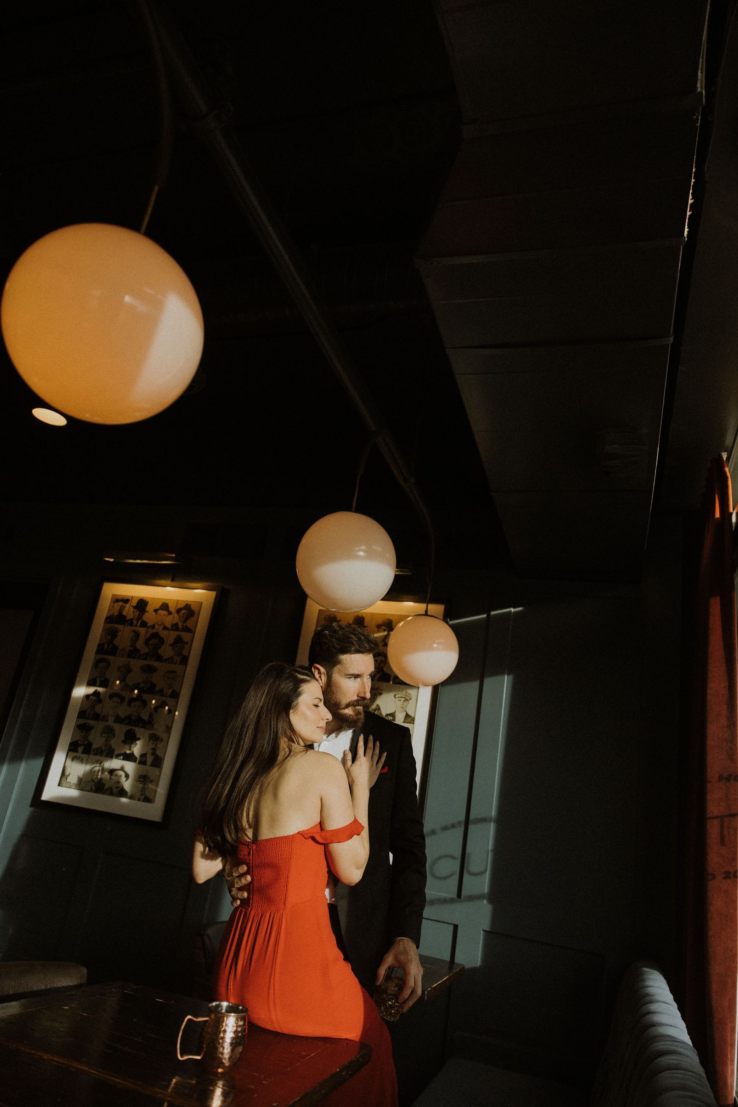 A series of dimly lit indoor photos showing a person in an orange top dancing under round paper lanterns.