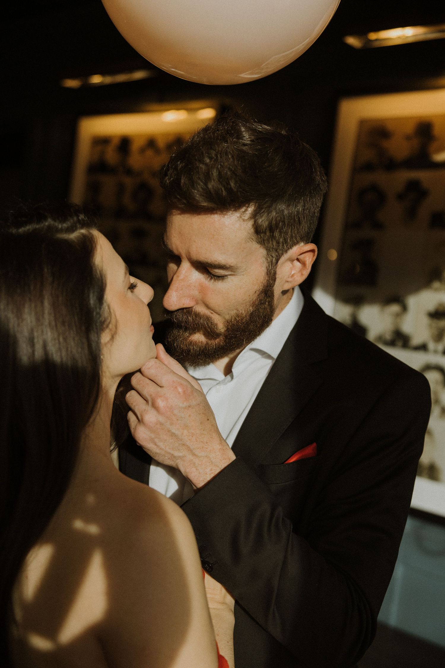 A romantic moment between a couple in formal attire as they share an intimate embrace at an indoor venue.