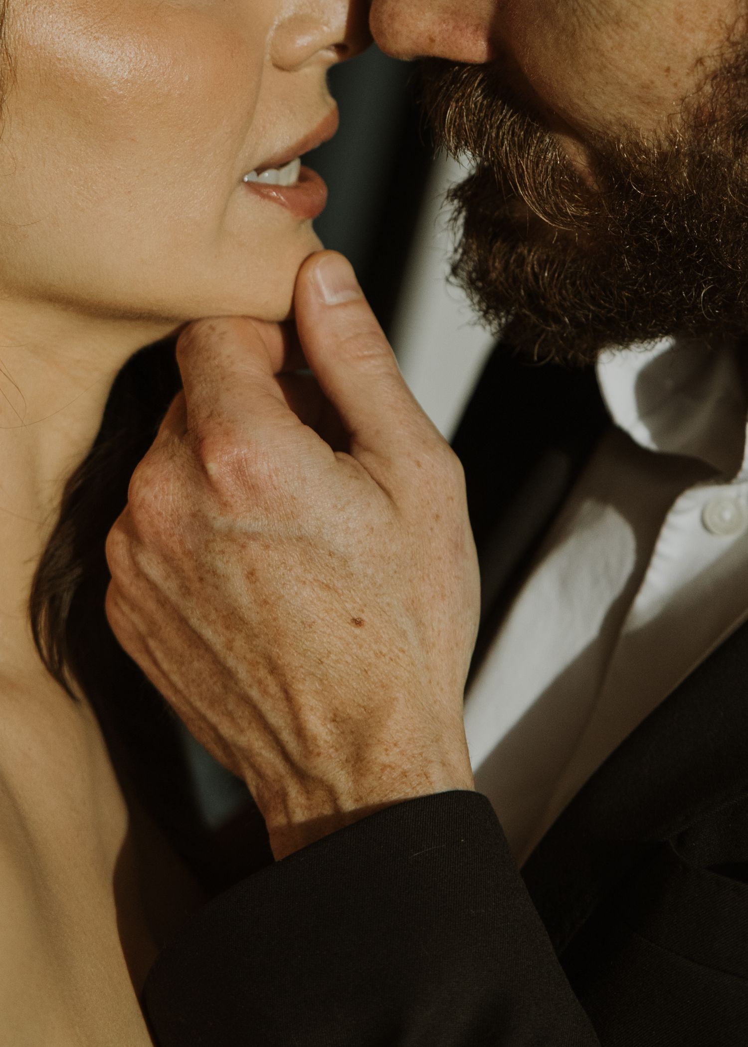 Close-up of a hand gently touching a neck and jawline in an intimate black and white portrait.