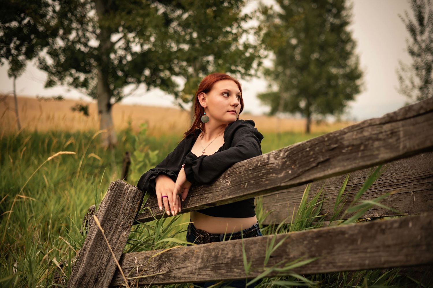 A senior portrait of a girl standing along a wood fence at the Feryn Conservation area in Spokane Washington.