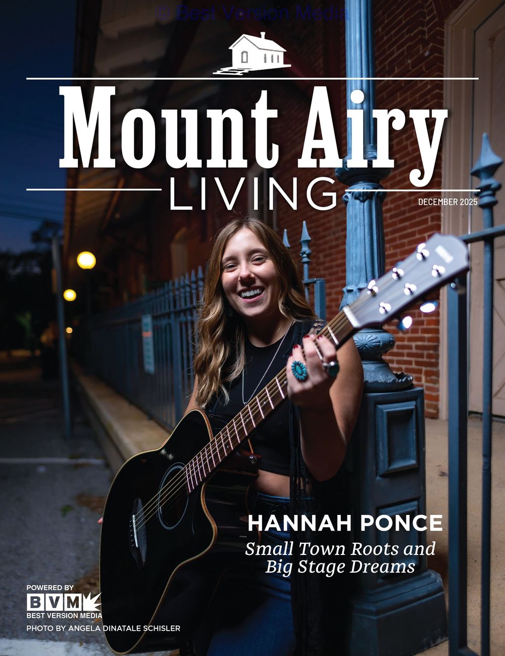 Magazine cover of Mount Airy Living featuring someone playing an acoustic guitar on a brick-lined street at dusk. Hannah Ponce