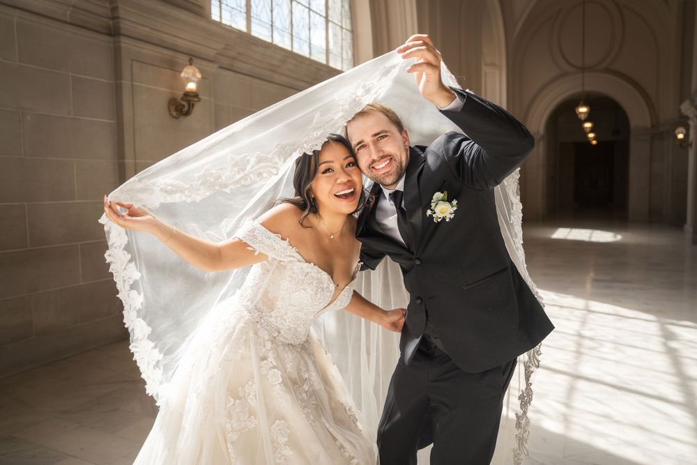 Joyful couple dances together in a bright sunlit venue with high windows and stone walls.