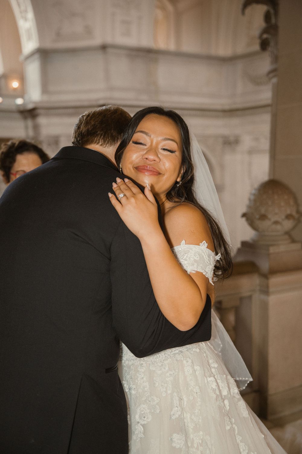 Intimate wedding moment captured in elegant marble hallway with classical architecture.