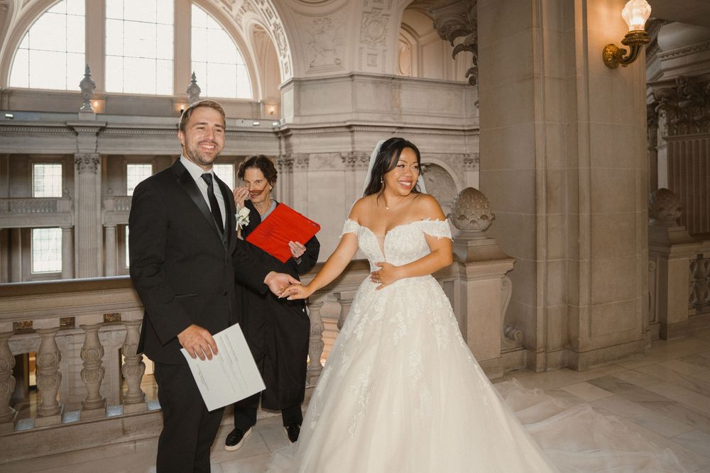 A bride and groom dance together in an elegant stone hallway with arched architectural details.