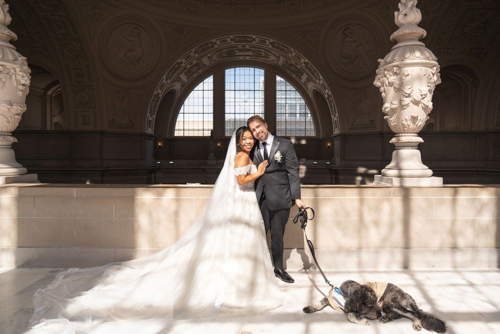 Elegant wedding portraits in historic building with marble columns and arched windows.