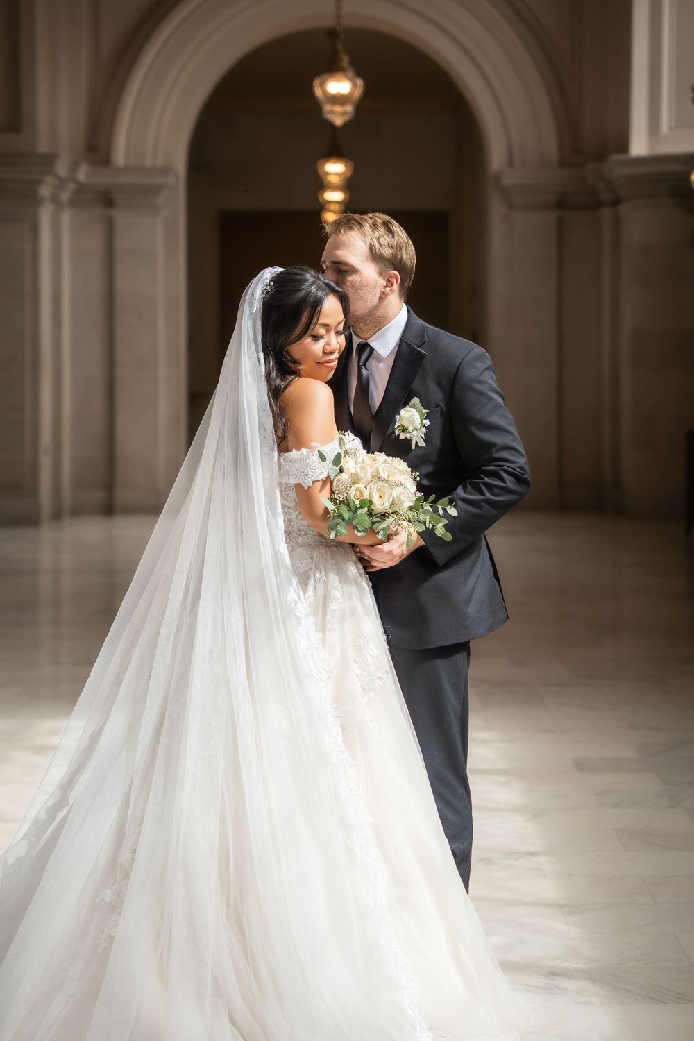 Romantic wedding portraits captured in a sunlit classical corridor with arched architecture.