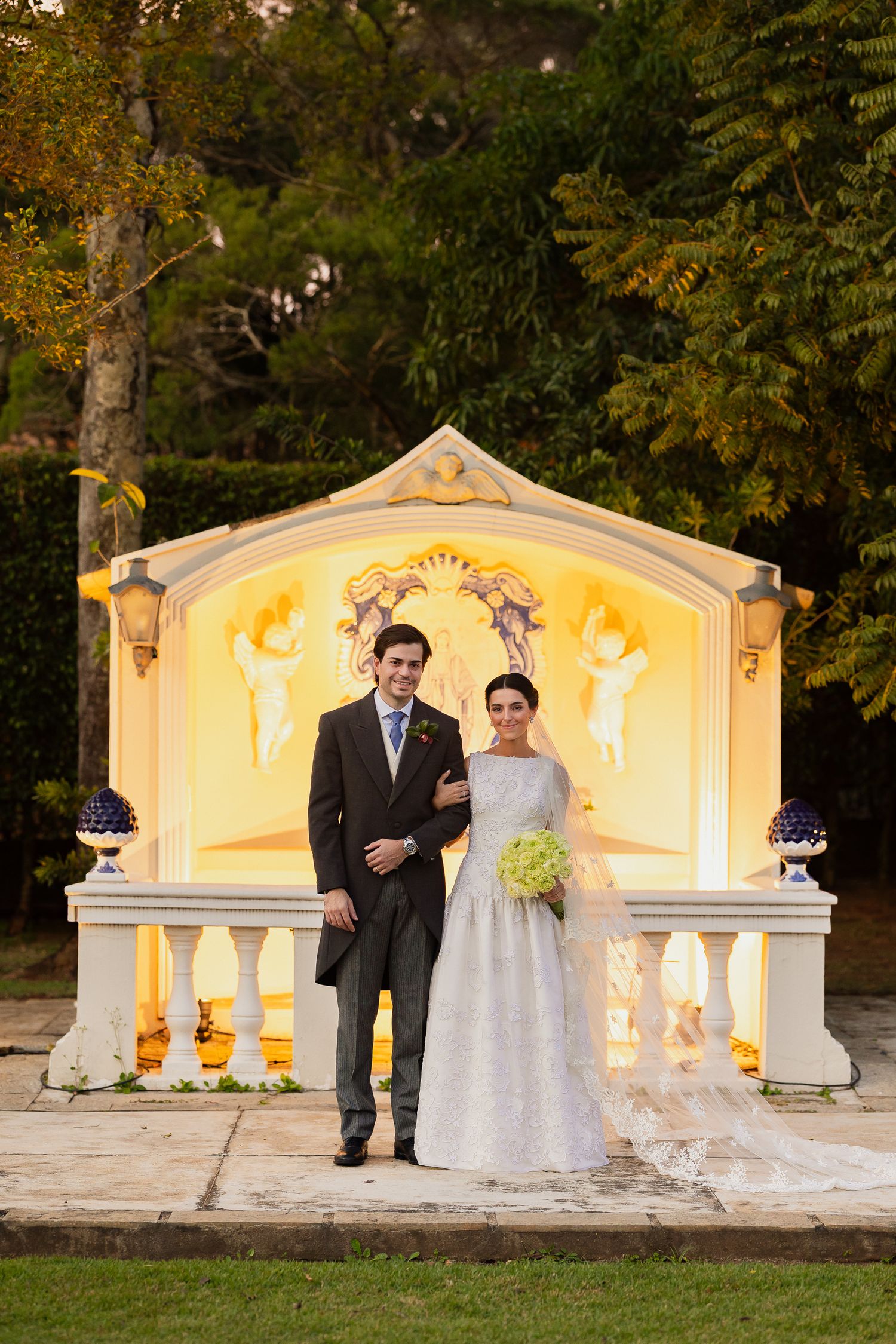 Outdoor wedding ceremony at sunset with illuminated stone backdrop and autumn foliage.