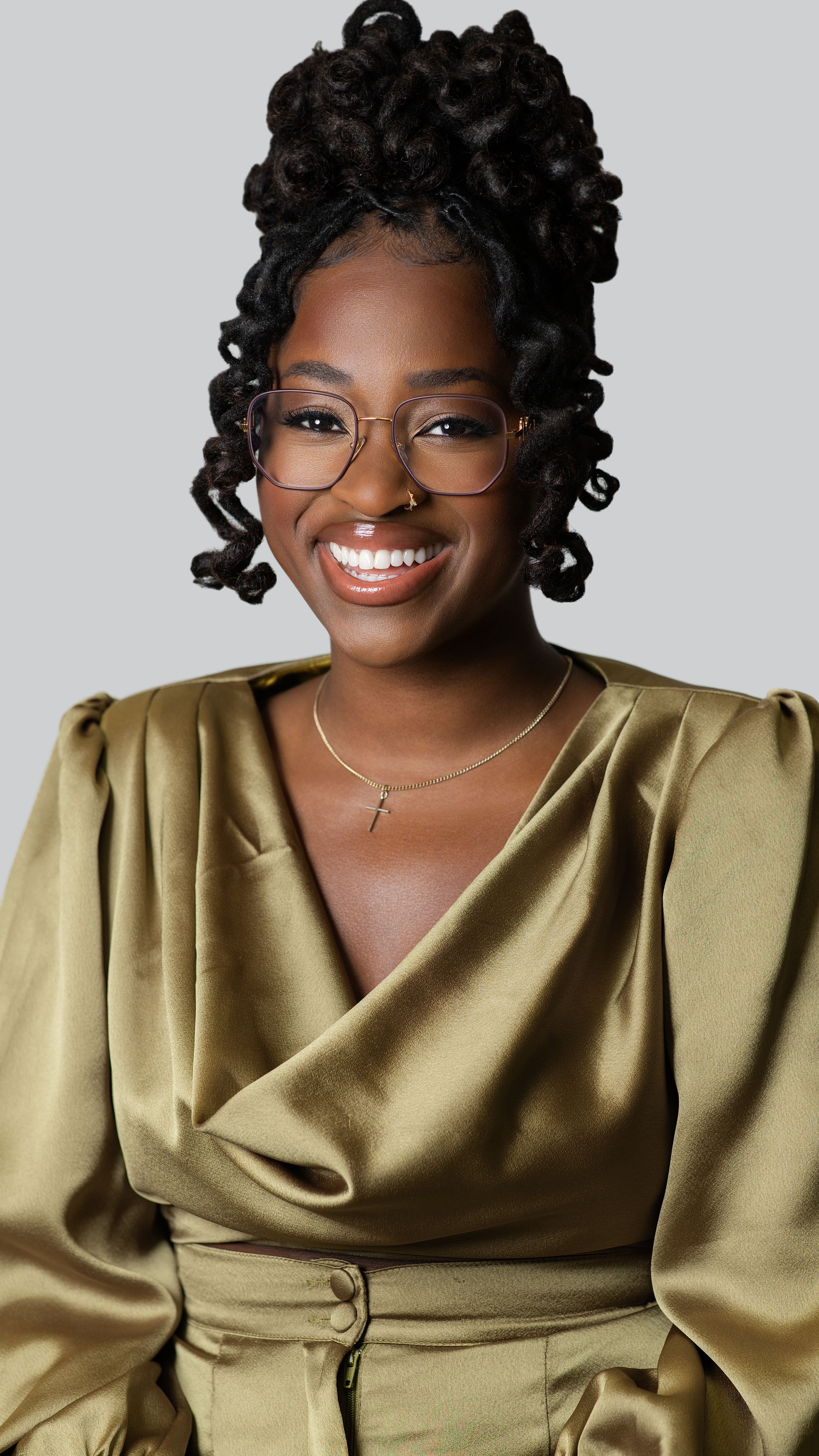 Elegant portrait in olive satin dress against neutral grey studio background.