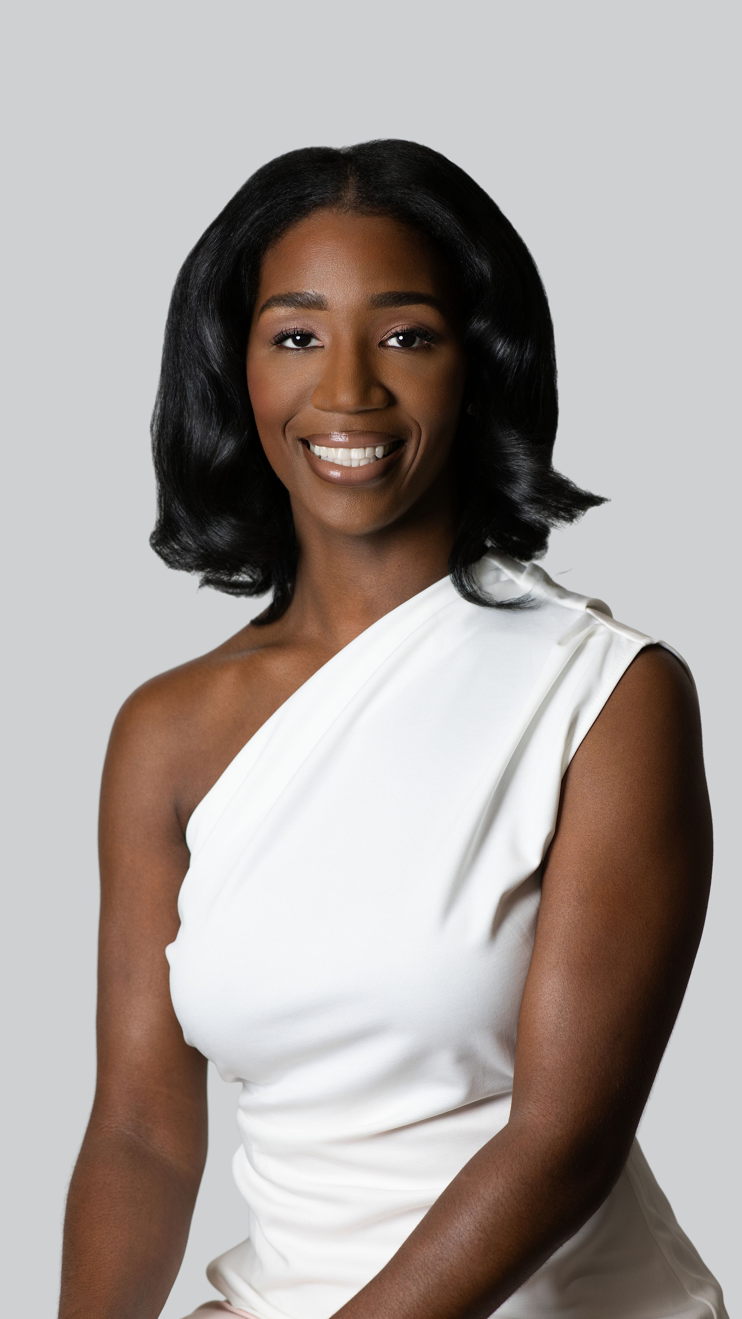 Stylish white asymmetrical sleeveless top photographed against light grey background.