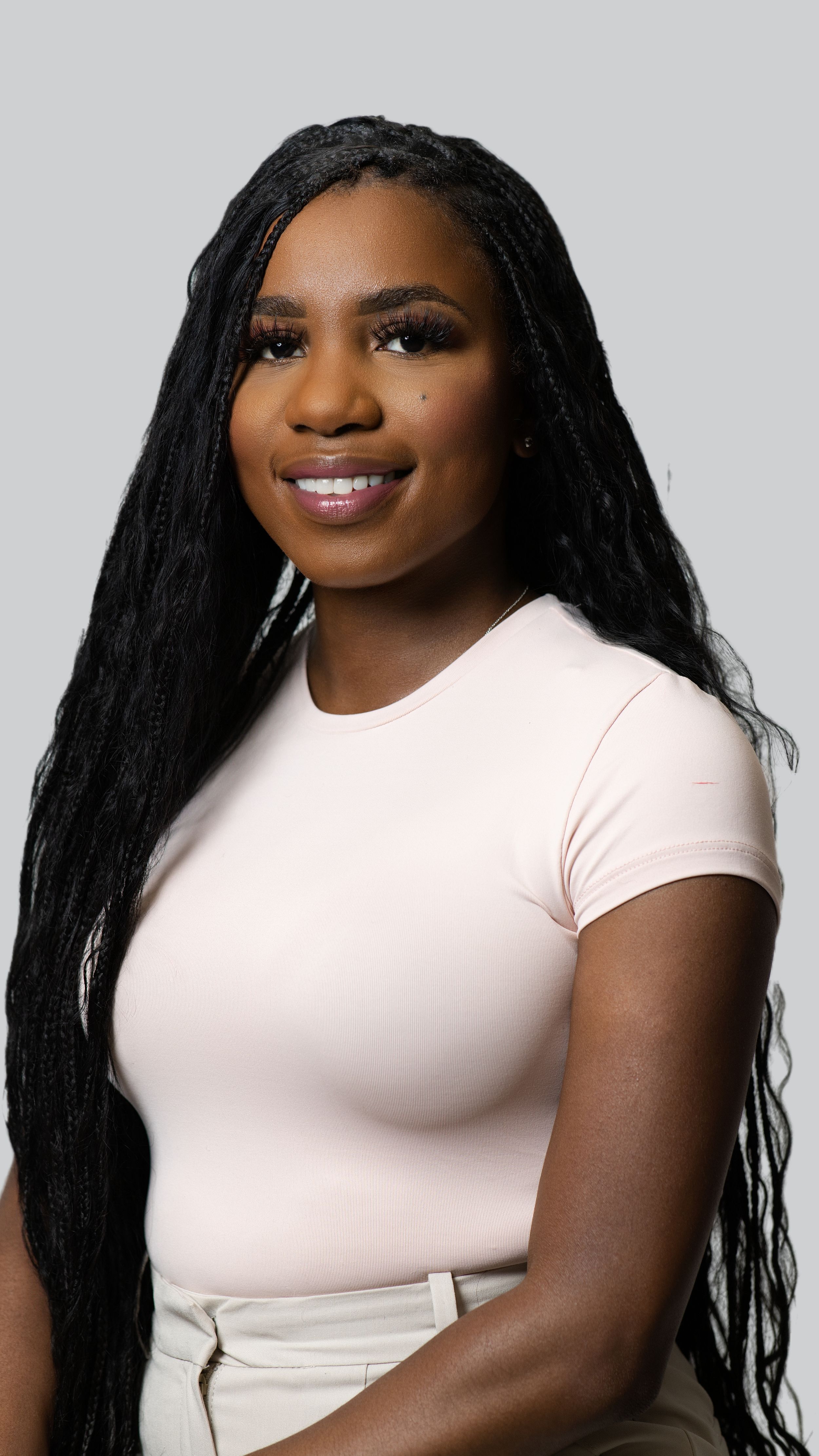 Athletic portrait in fitted white t-shirt with long dark hair against light grey background.