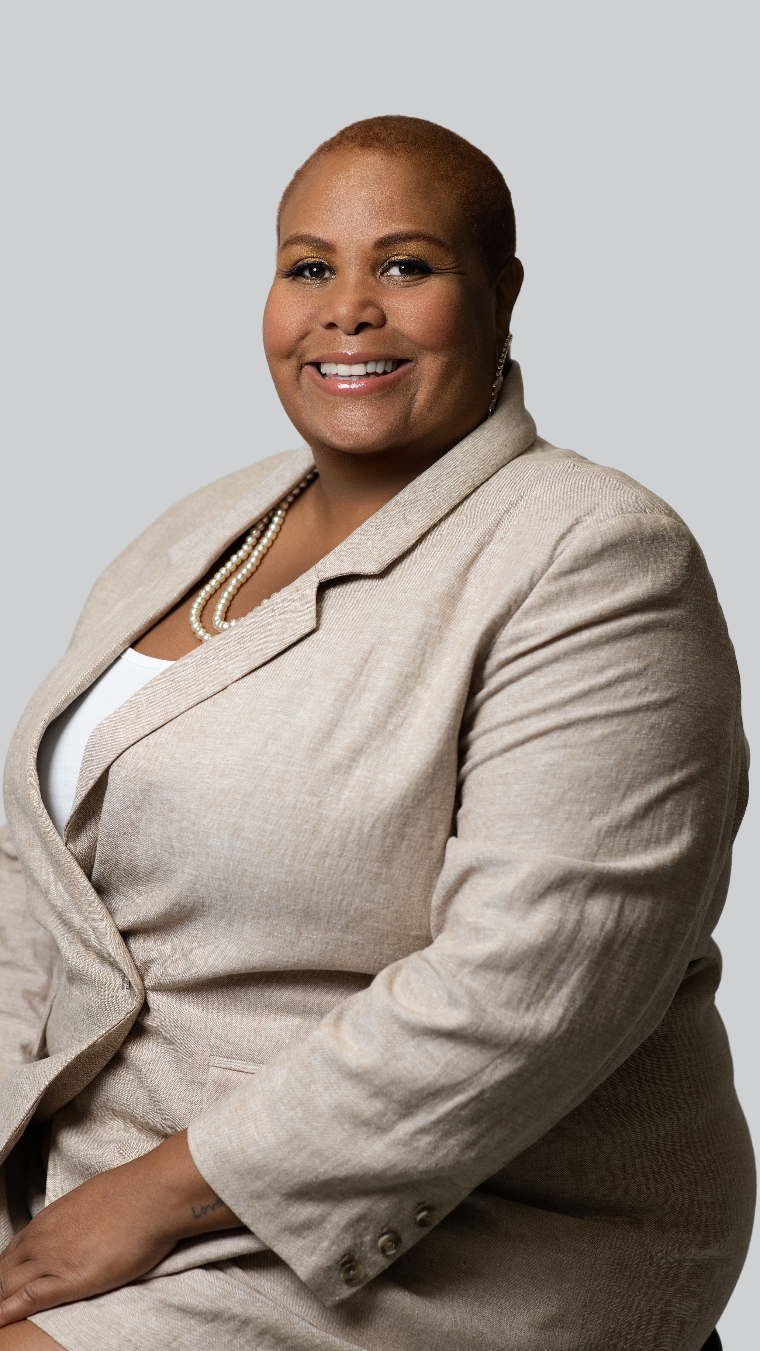 Professional headshots showing warm smiles and a beige blazer against a light background.