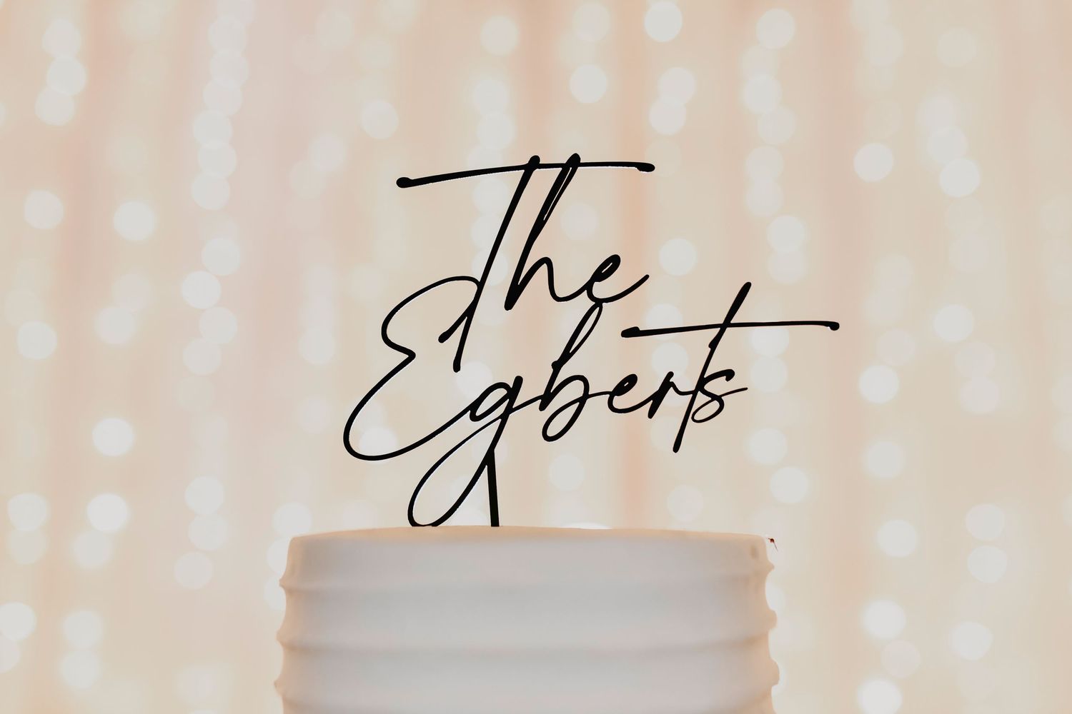 Close-up of textured white wedding cake with candlelight reflecting from surrounding glass votives.
