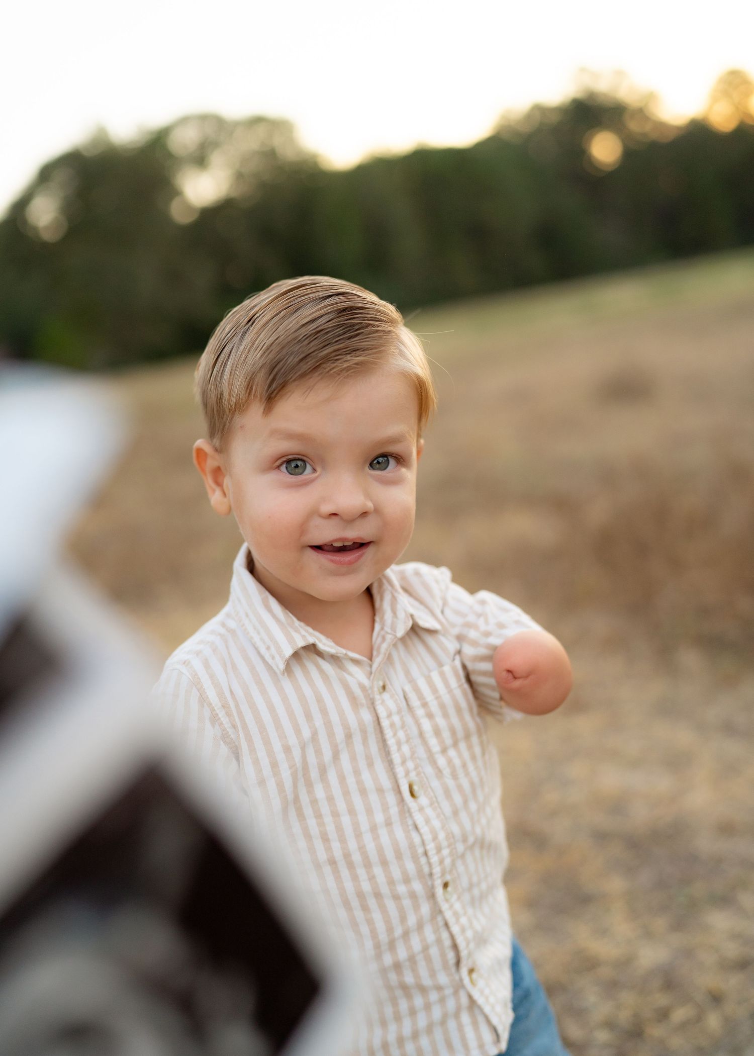 Toddler playing peekaboo with ultrasound image during baby announcement photoshoot.