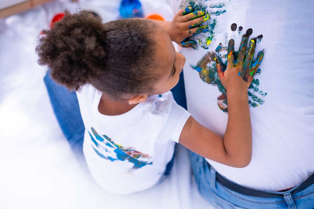 Kid painting on parent with finger paint