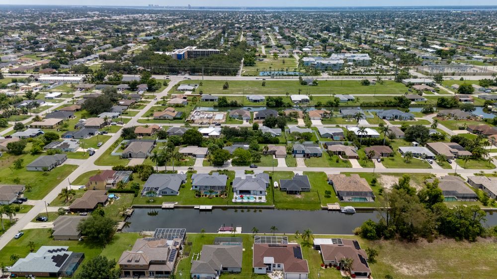 Aerial panoramic view of a Florida residential neighborhood with canals, homes, and palm trees.