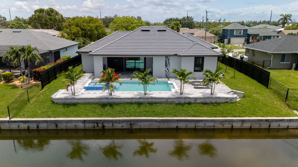 Modern Florida home with a rectangular pool, palm trees, and canal waterfront backyard.