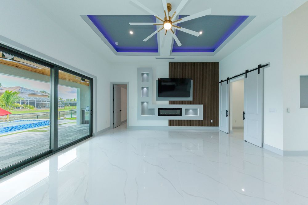 Elegant living room featuring blue tray ceiling, ceiling fan, barn door, fireplace, and built-in shelving.