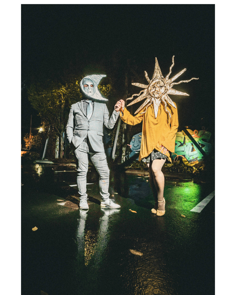 Two figures in contrasting gray and yellow costumes perform a nighttime dance routine with dramatic lighting effects.