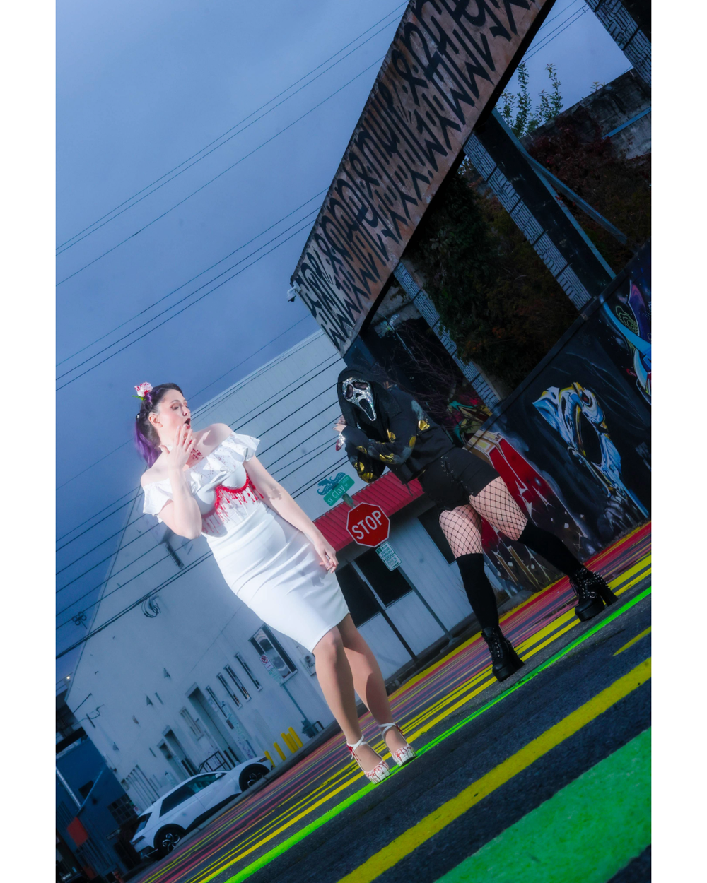 Person in white attire performs on a colorful stage with rainbow stripes under dramatic lighting at night.
