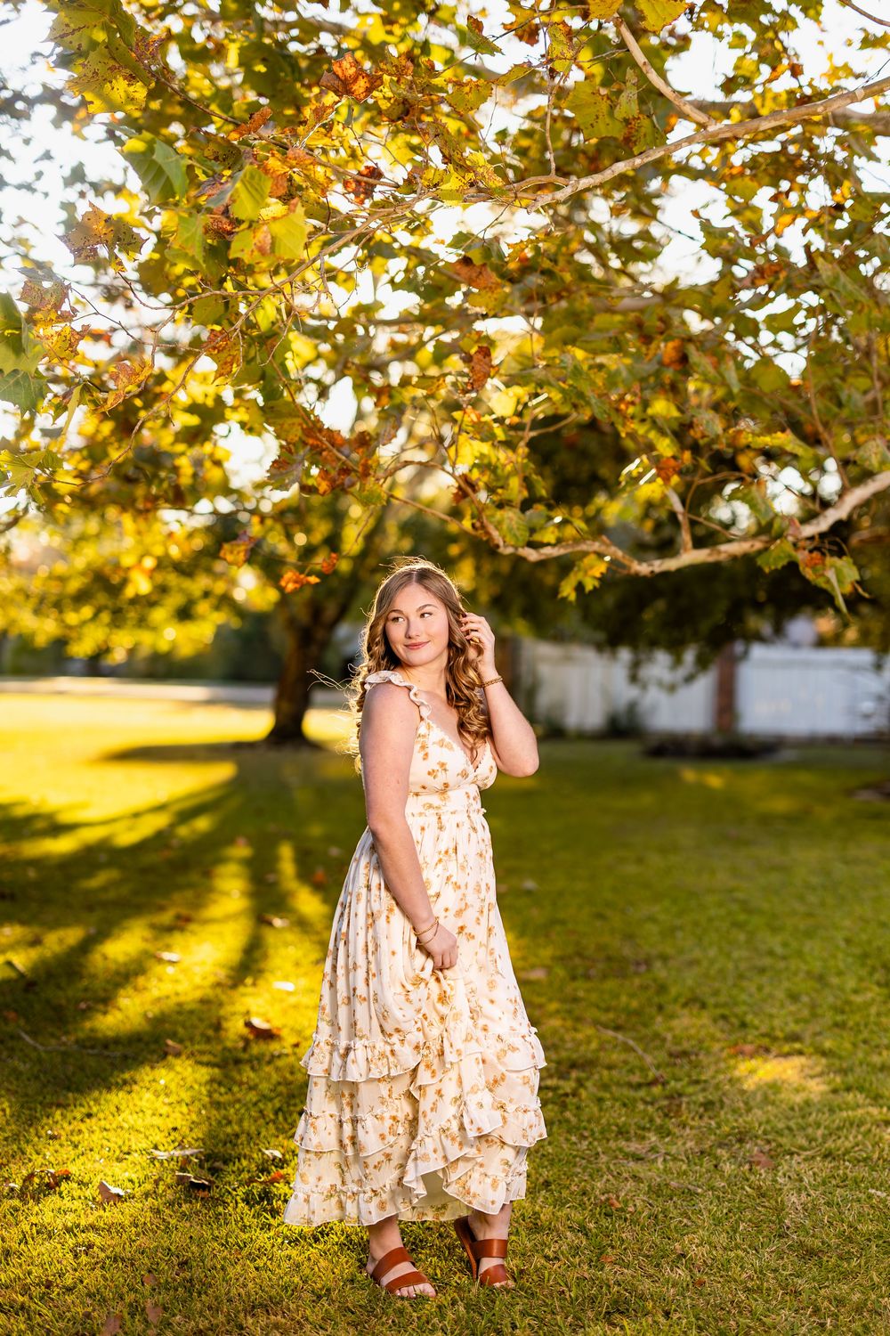Cream floral dress captured in warm evening sunlight under autumn trees.