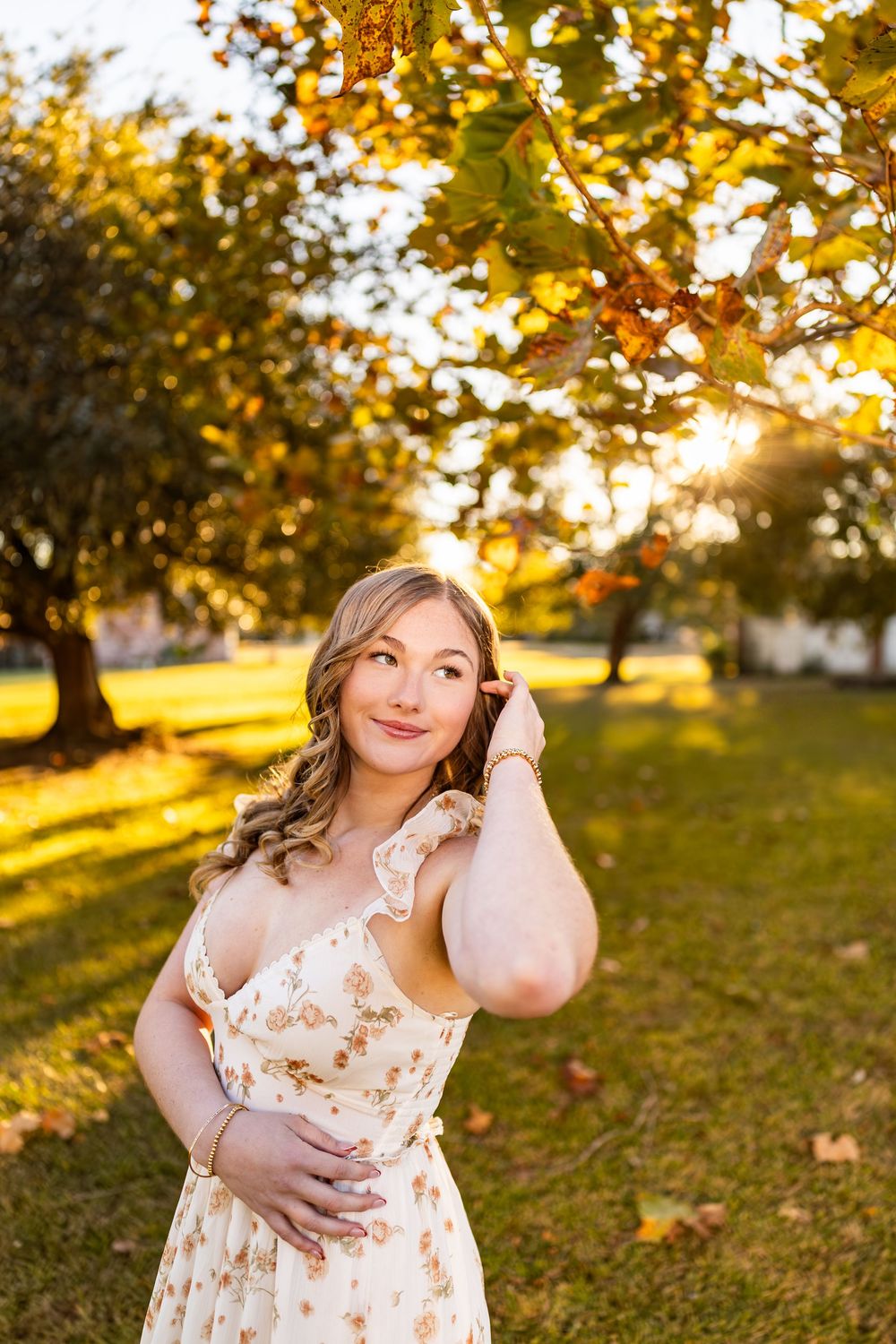 Portrait in floral sundress against golden sunset in autumn park setting.