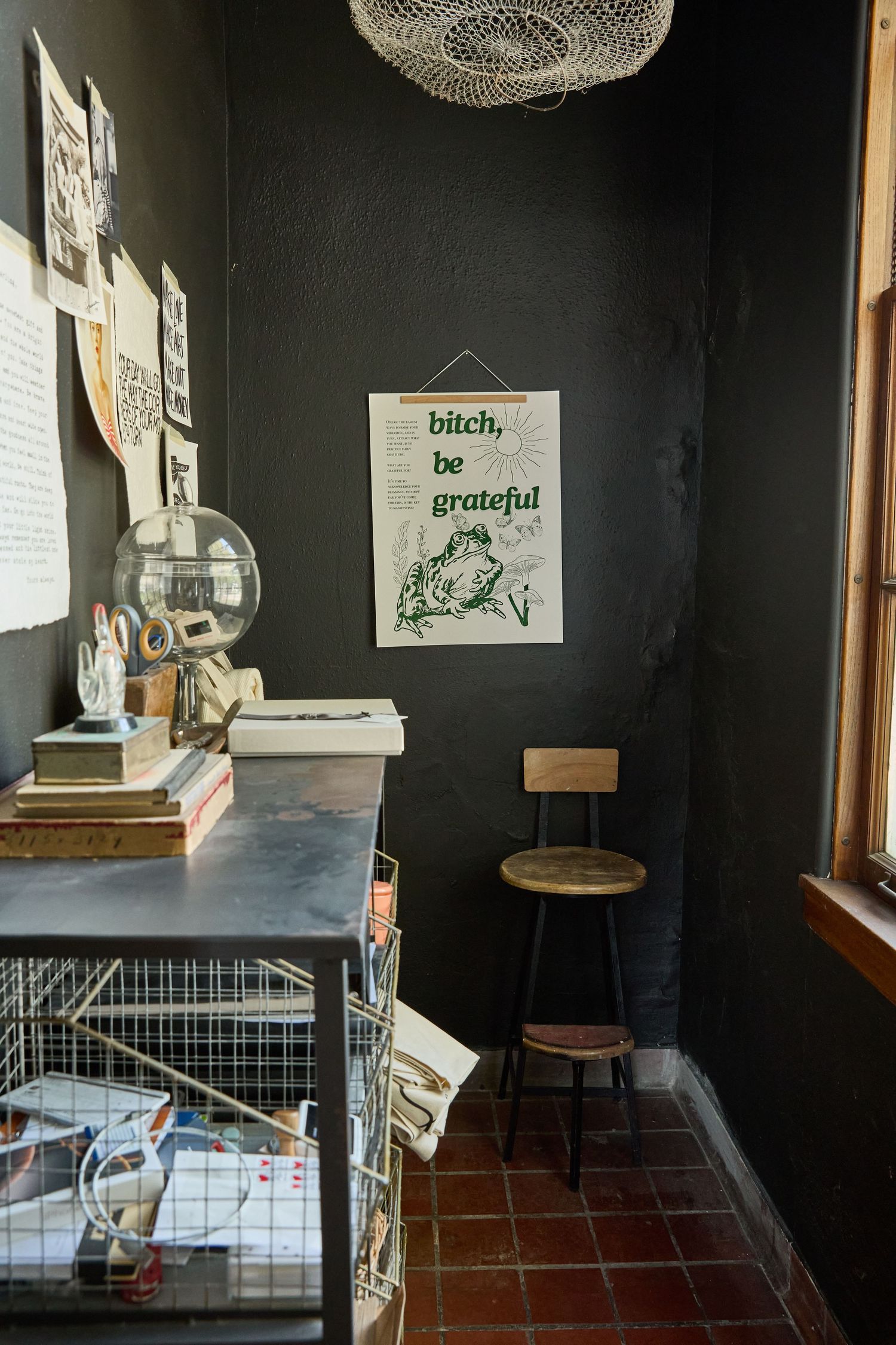 Interior view of a dark room with black walls, pendant lights, and various framed items mounted on display.