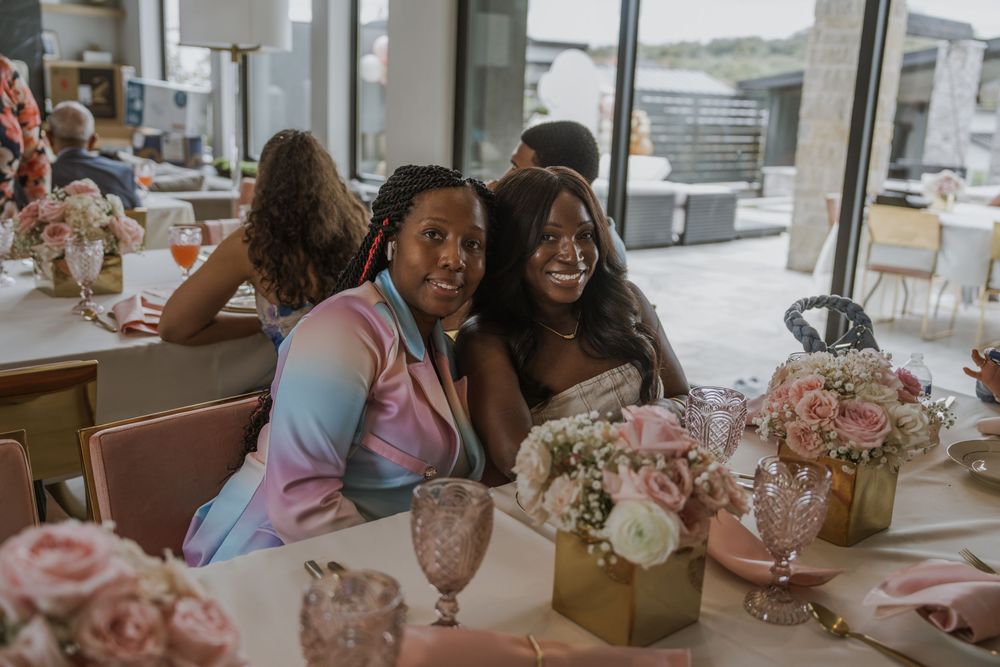 Friends celebrating at decorated table with pink floral centerpieces and glassware.