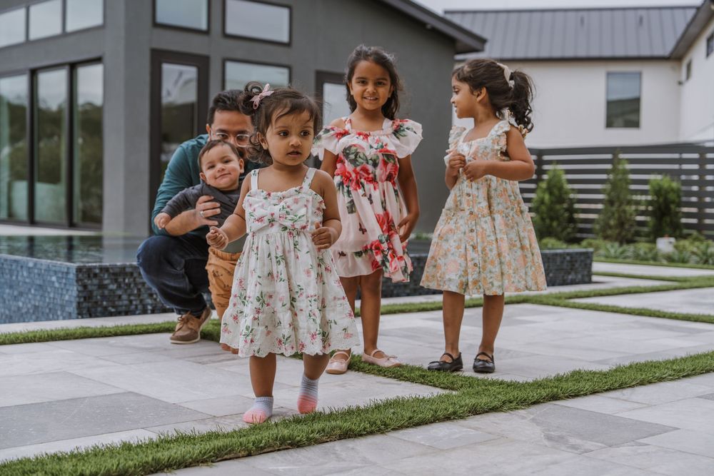 A group in floral dresses stands together on a lawn outside a modern building.