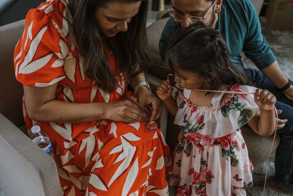Family members examining something together while wearing floral print dresses.