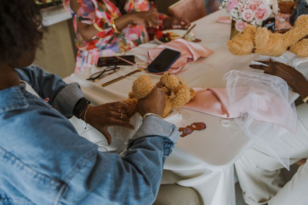 Hands holding and examining teddy bear decorations at a party table.