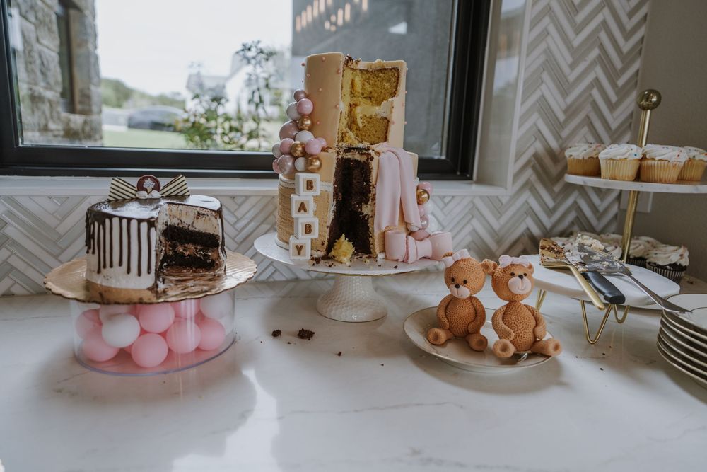 Elegant dessert table with cakes and teddy bear decorations at a baby shower.