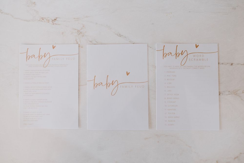 White paper wedding timeline documents with gold lettering on marble surface.
