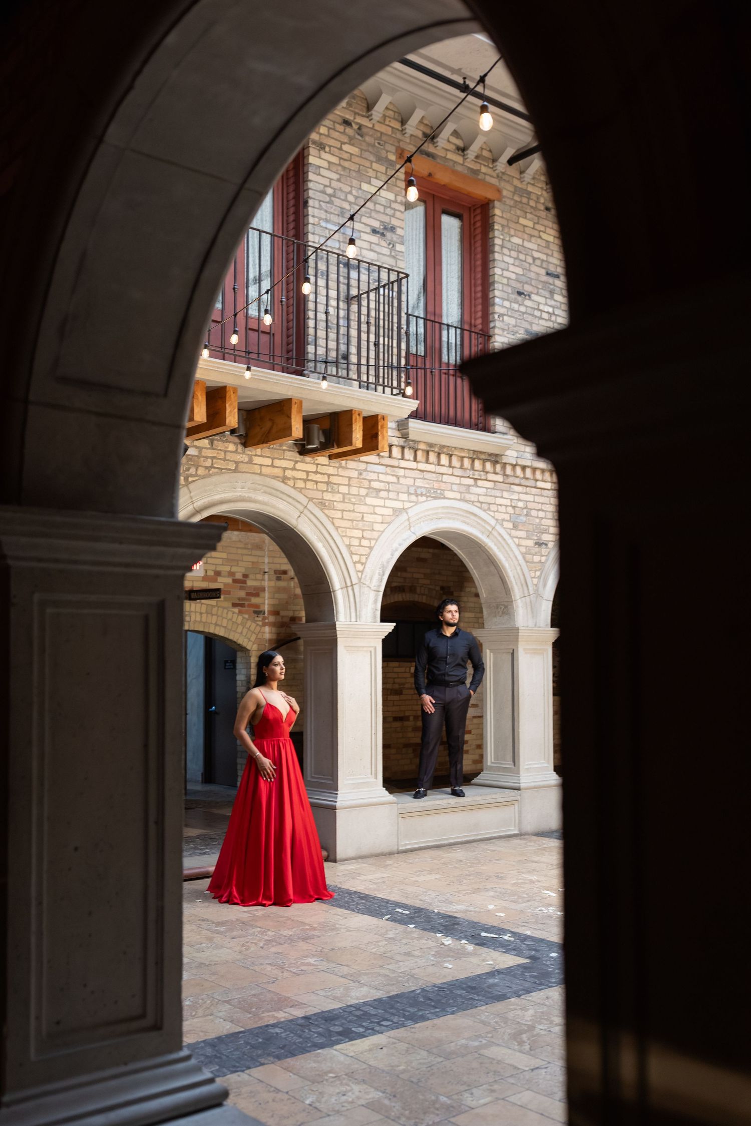 Artistic engagement photo series through stone archways showing couple in formal attire at historic building courtyard.