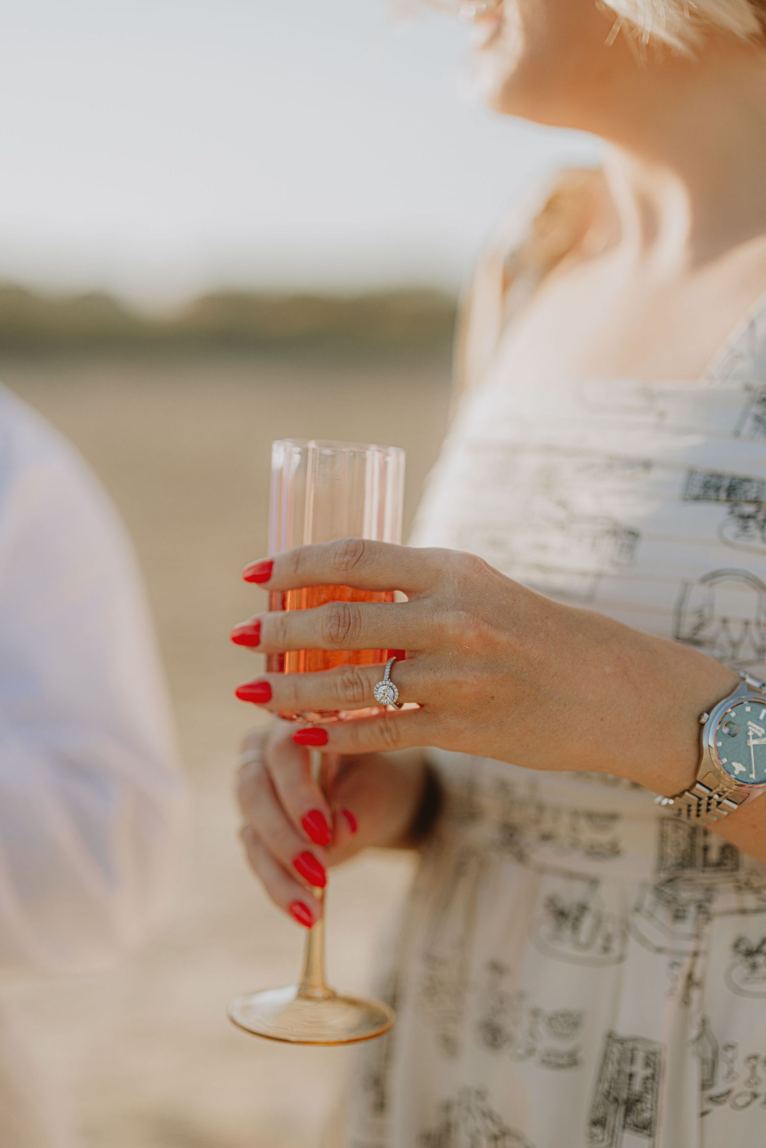 Close-up of hands with red nail polish holding champagne glasses during a celebration.