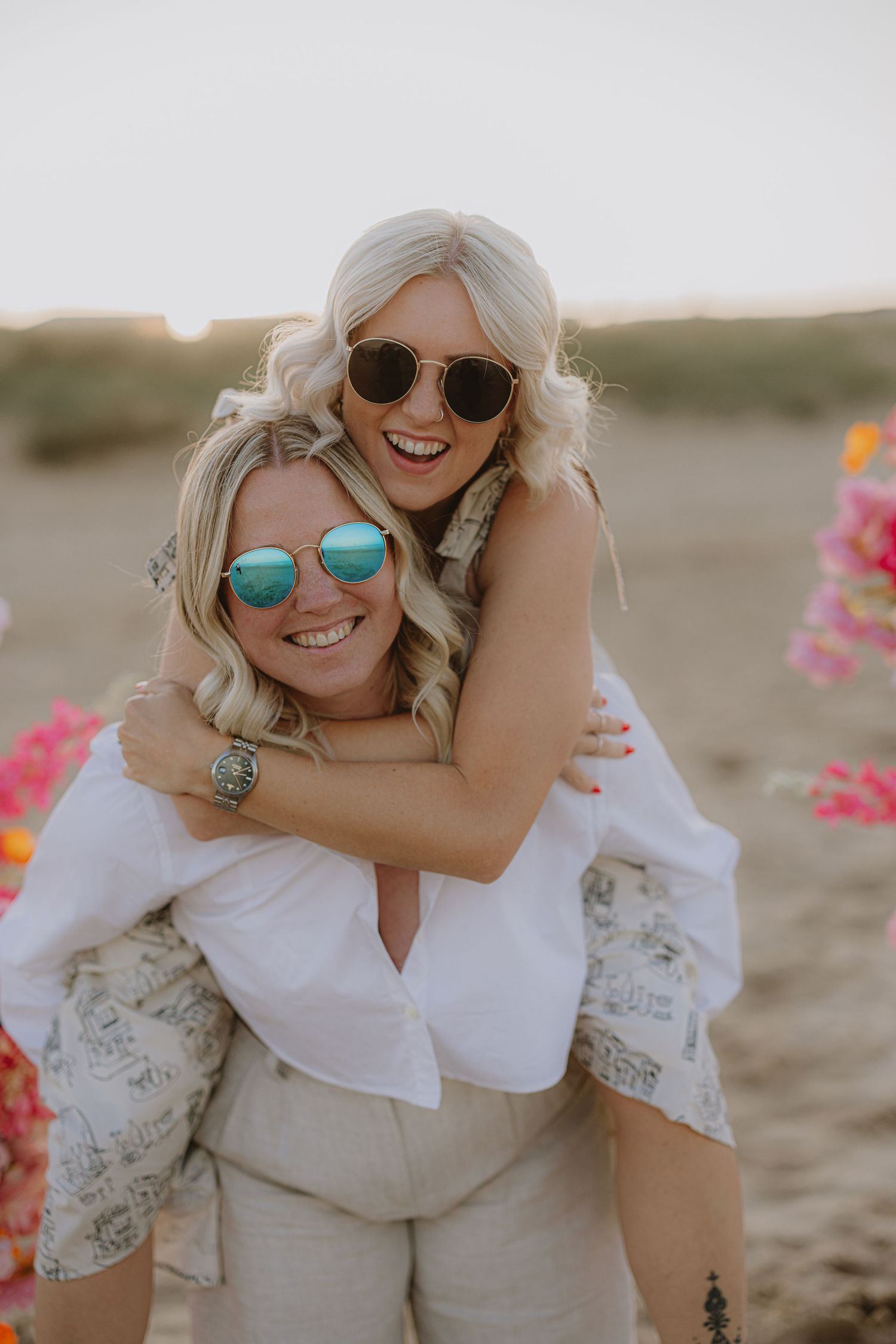 Candid beach photoshoot featuring sunglasses and playful embraces.