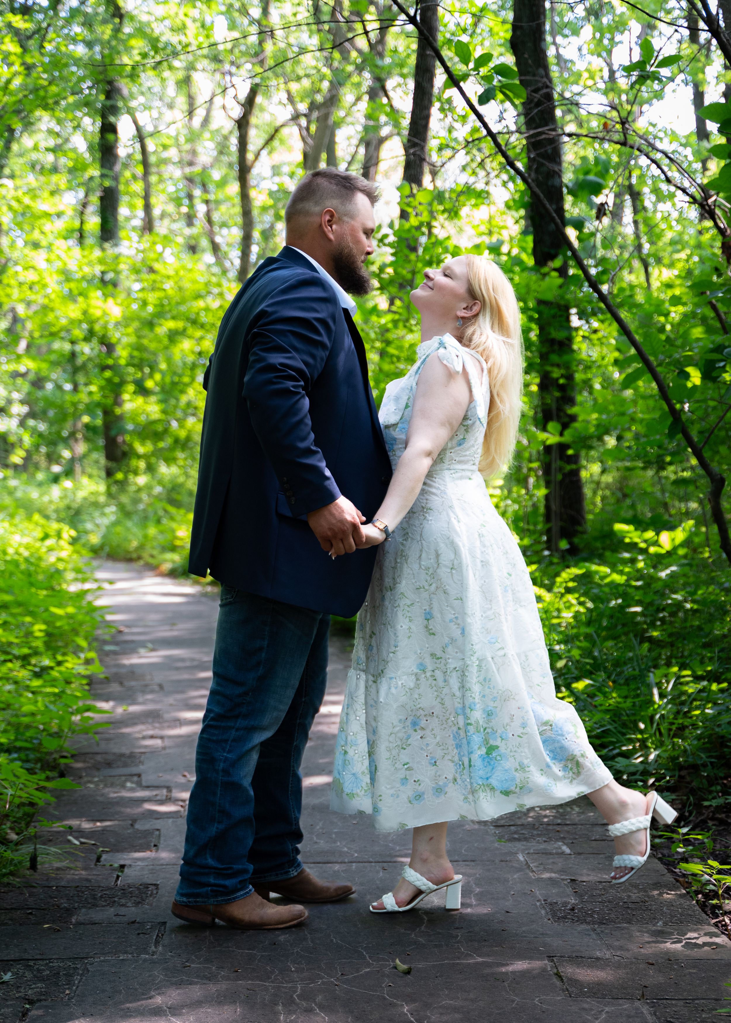 A series of romantic poses on a wooden boardwalk surrounded by green forest.
