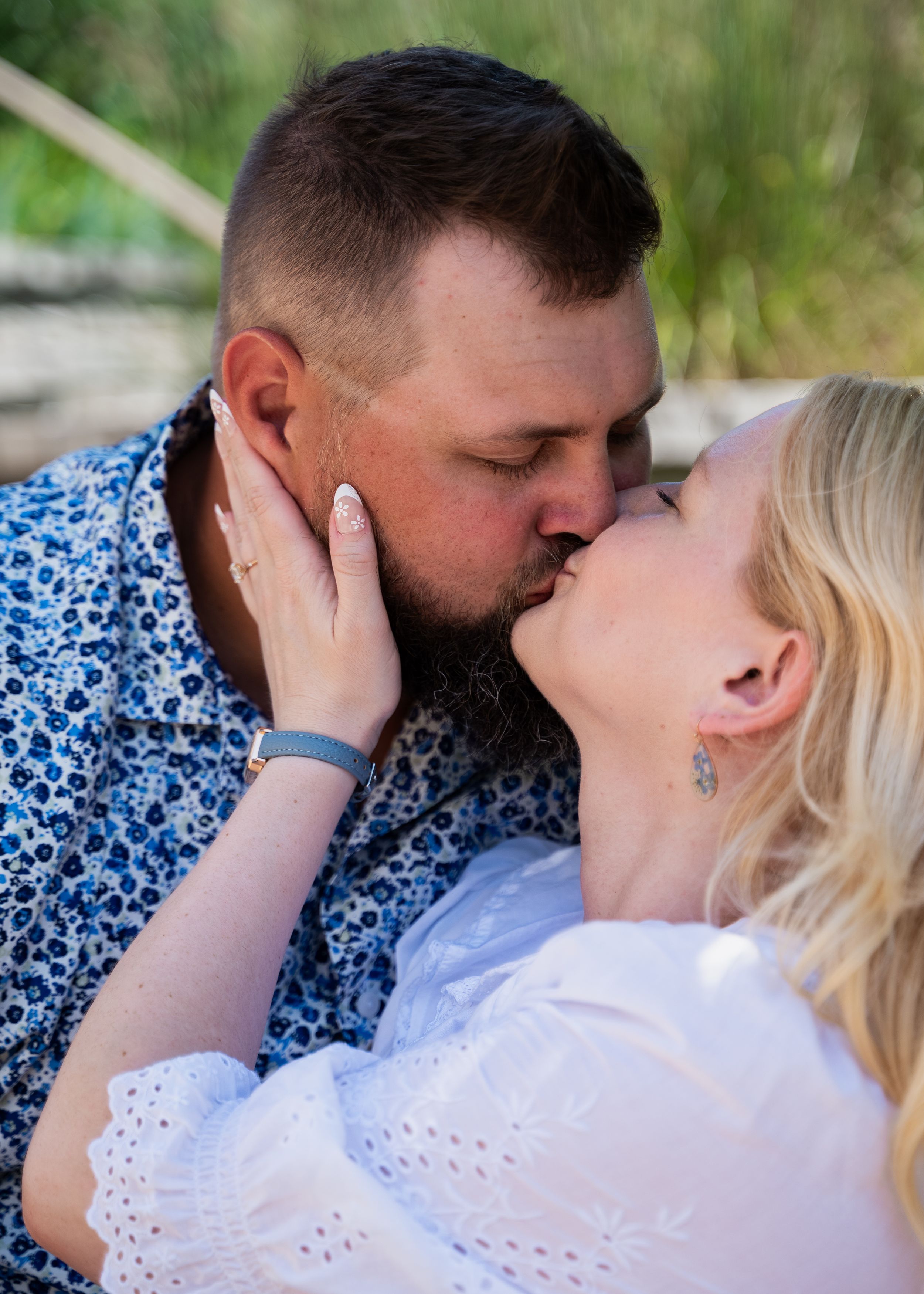 Tender moment shared between couple wearing blue floral shirt and white eyelet top.