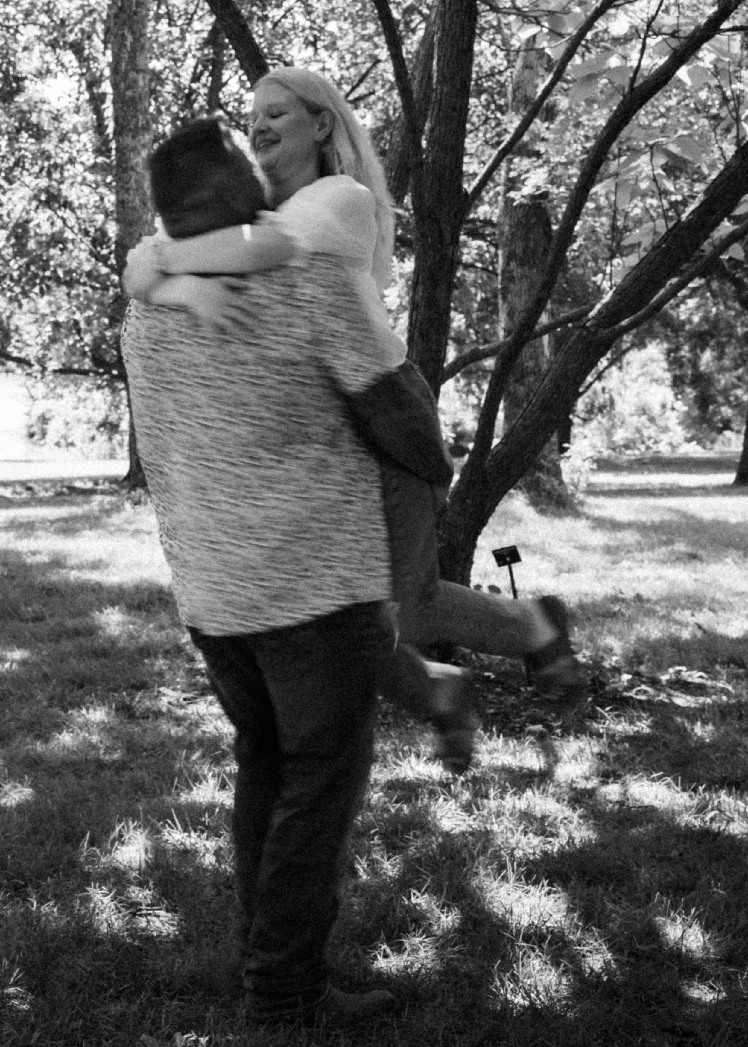 Couple sharing a romantic moment under a tree with dappled sunlight.