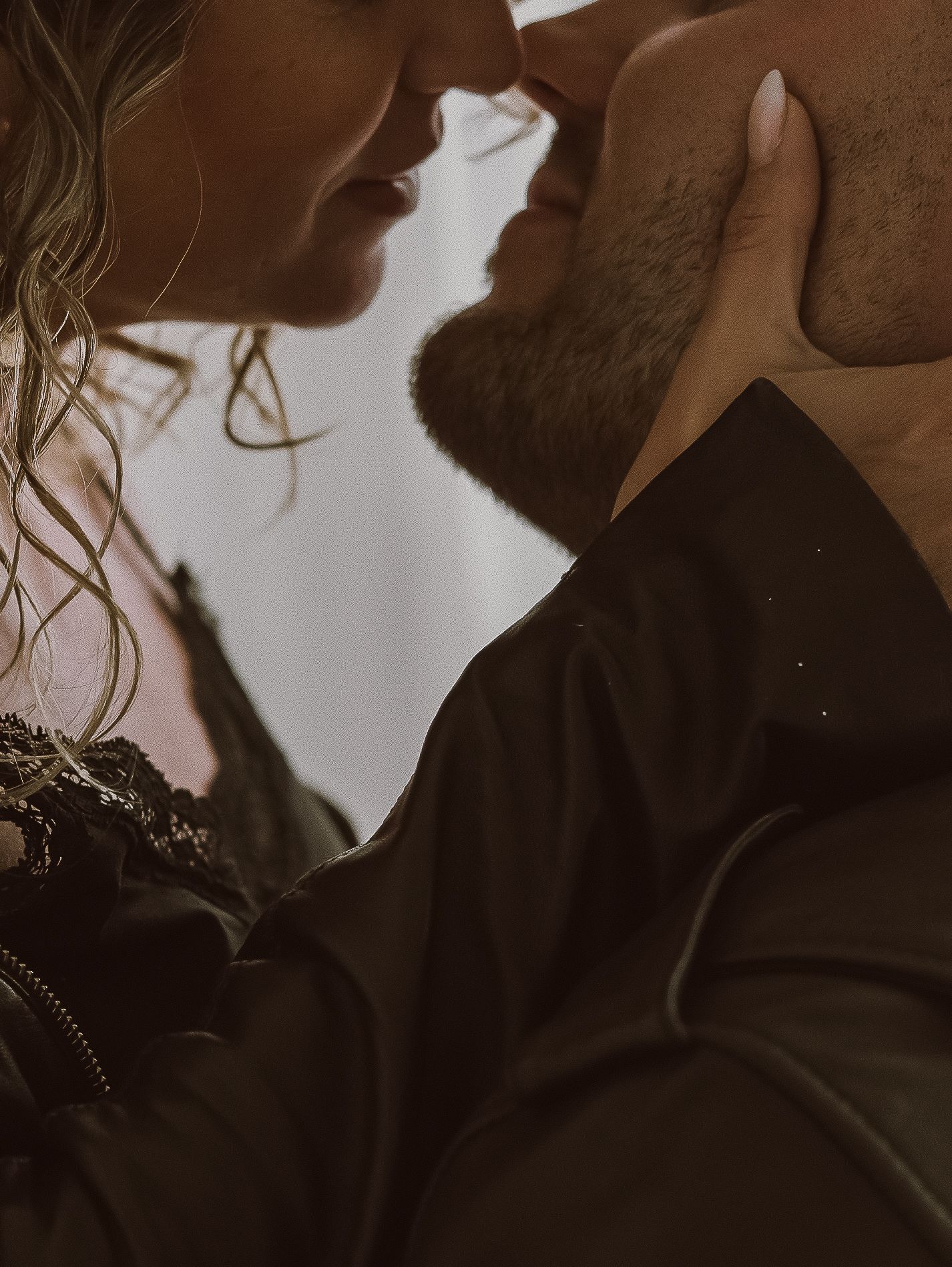 Close-up intimate silhouette of a couple sharing a tender romantic moment with sun-lit ambiance.