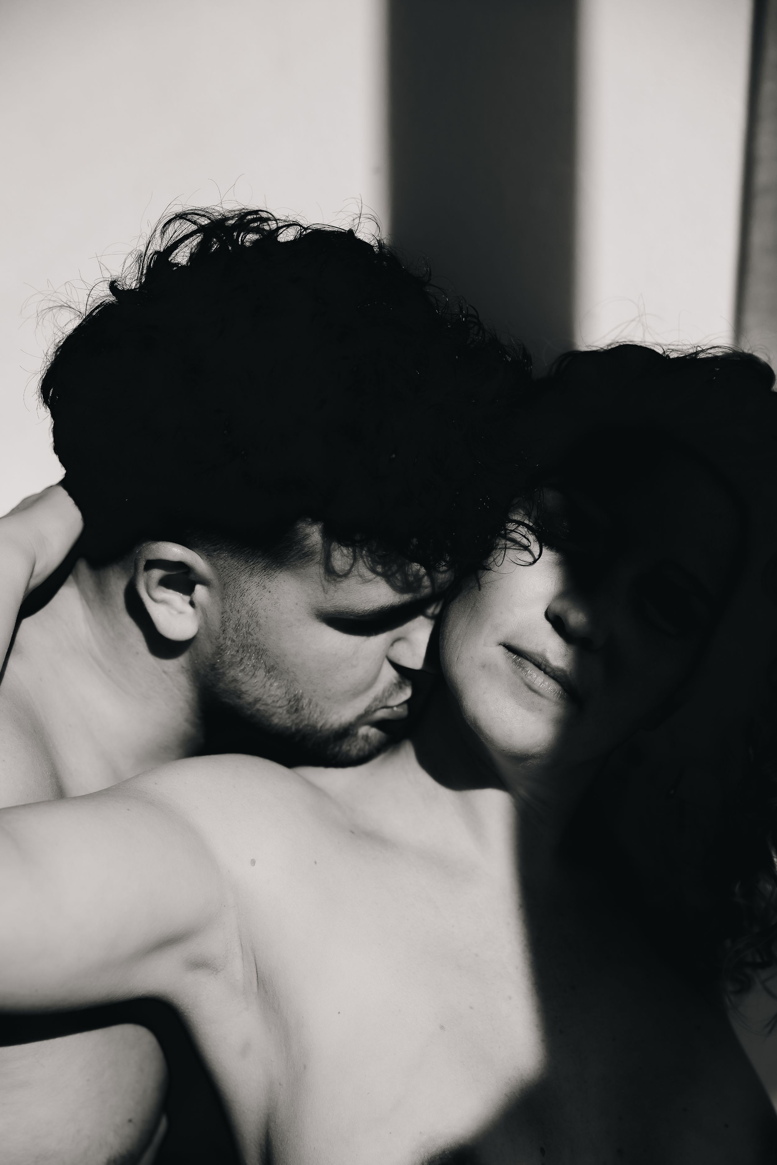 A black and white intimate photograph showing two people in a tender loving embrace.