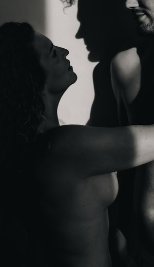 Dramatic black and white silhouettes of figures in an intimate pose create a moody artistic composition.