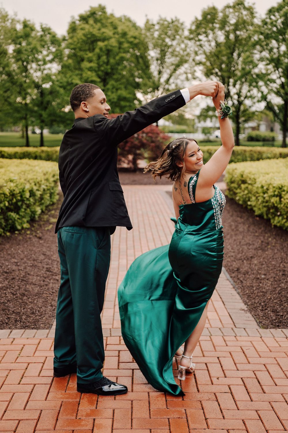 A couple in formal attire dance together under the rain on a brick pathway in Hershey, PA.