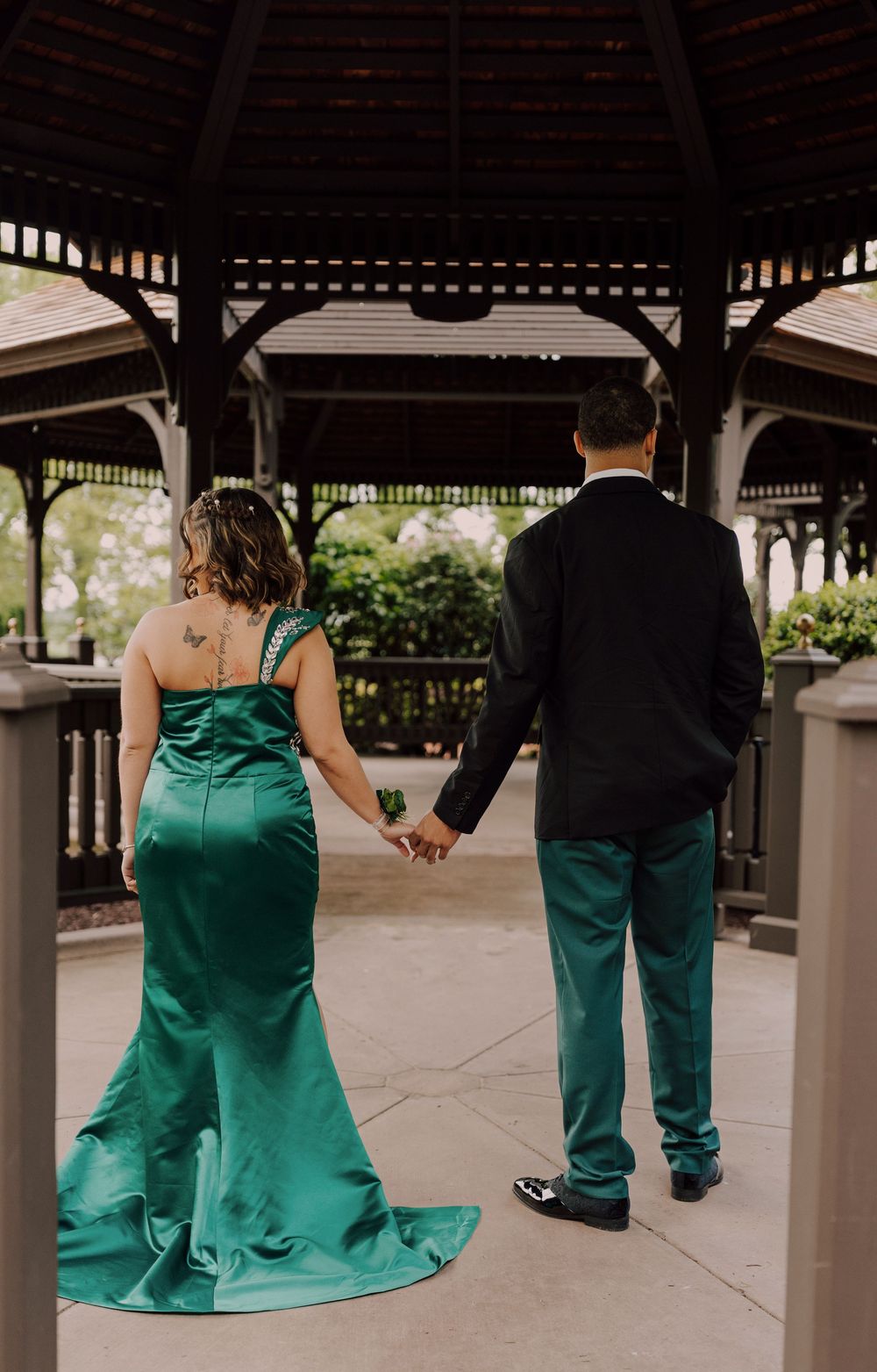 A couple in green formal attire hold hands for prom photoshoot at Hershey, PA.
