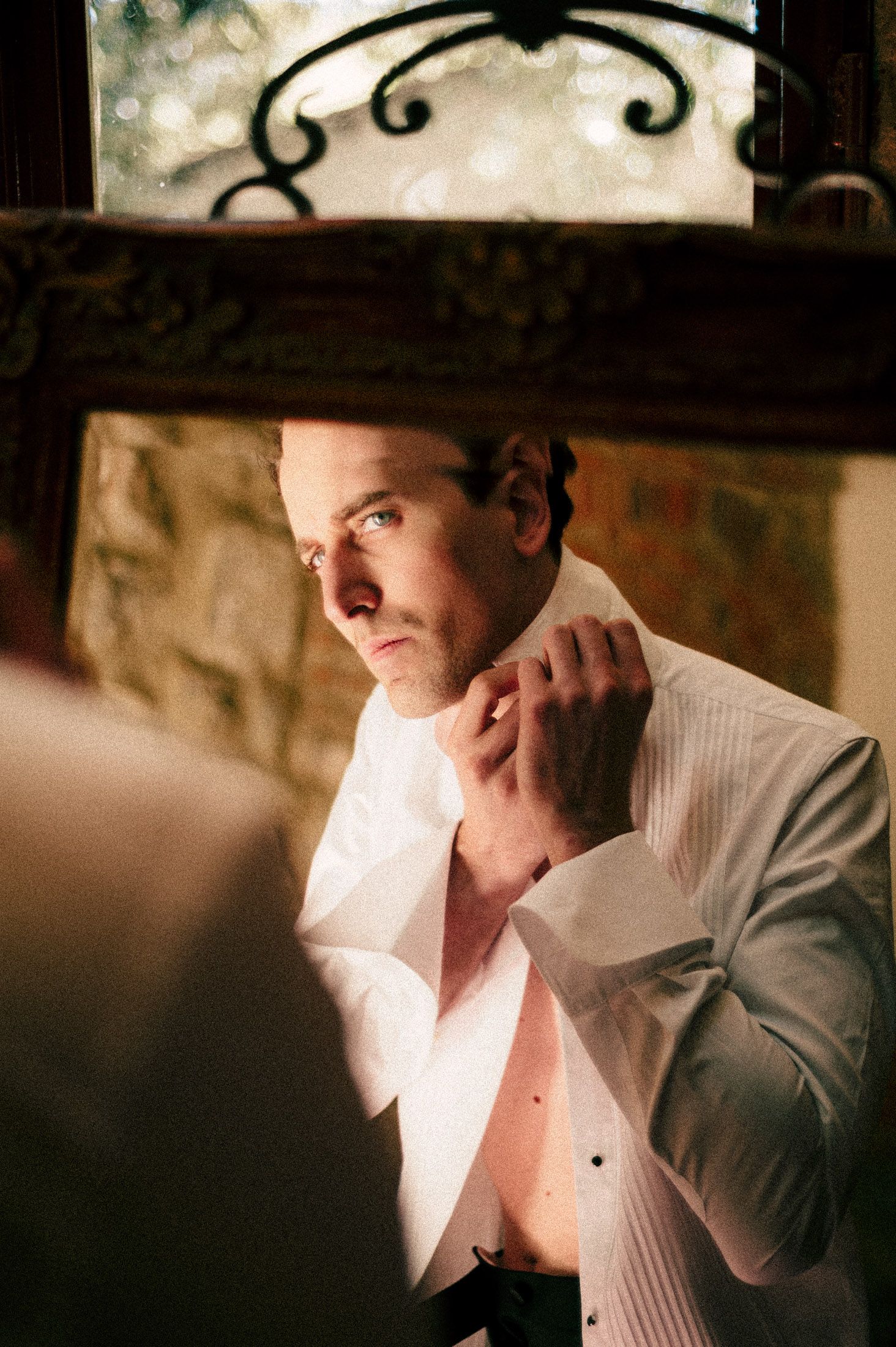 Person in a white shirt and black hat sits pensively in moody lighting.