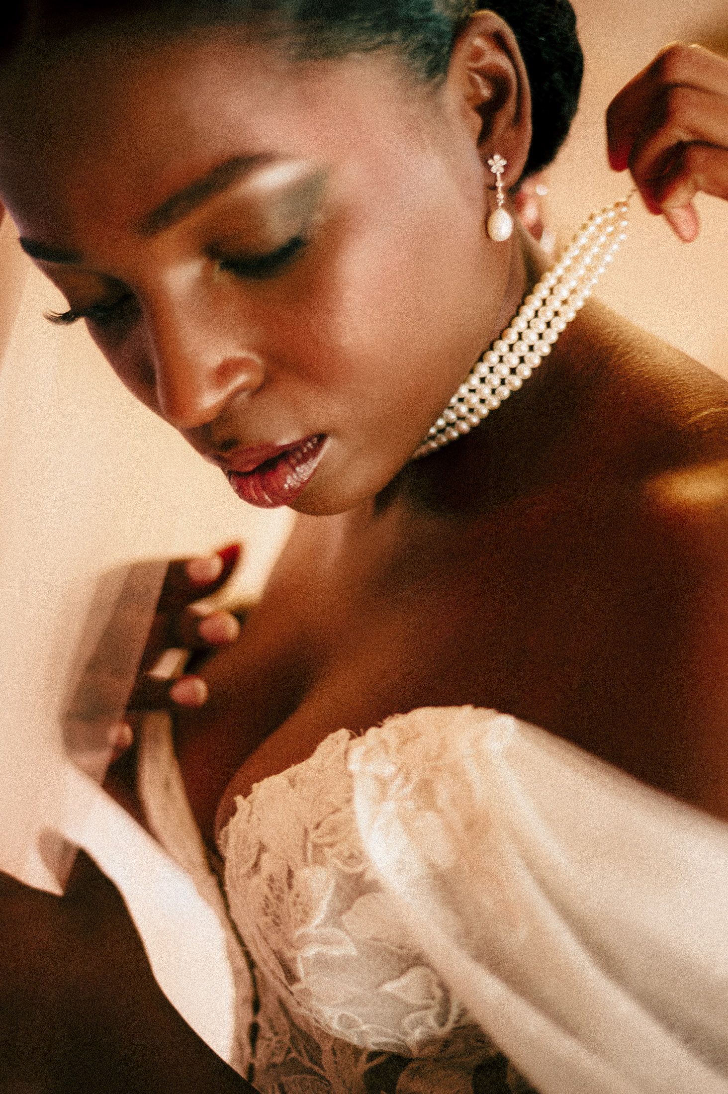 Fashion portrait in warm tones showing elegant pearl earrings and delicate lace details in artistic composition.