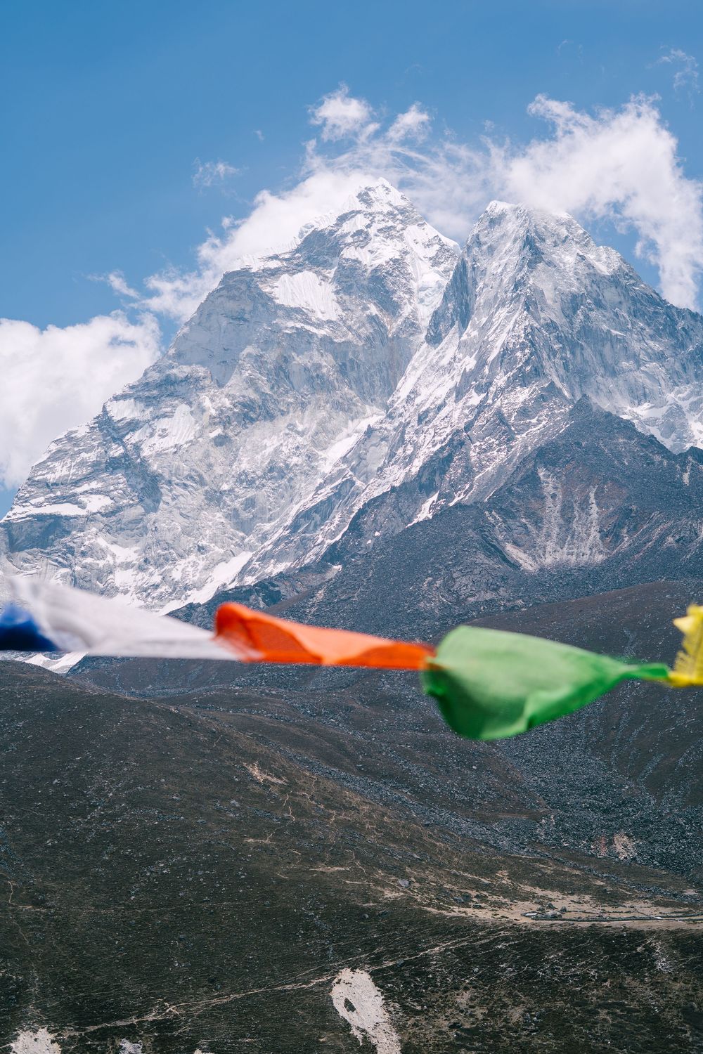 Snow-capped Himalayan mountain peak with colorful prayer flags fluttering in foreground.