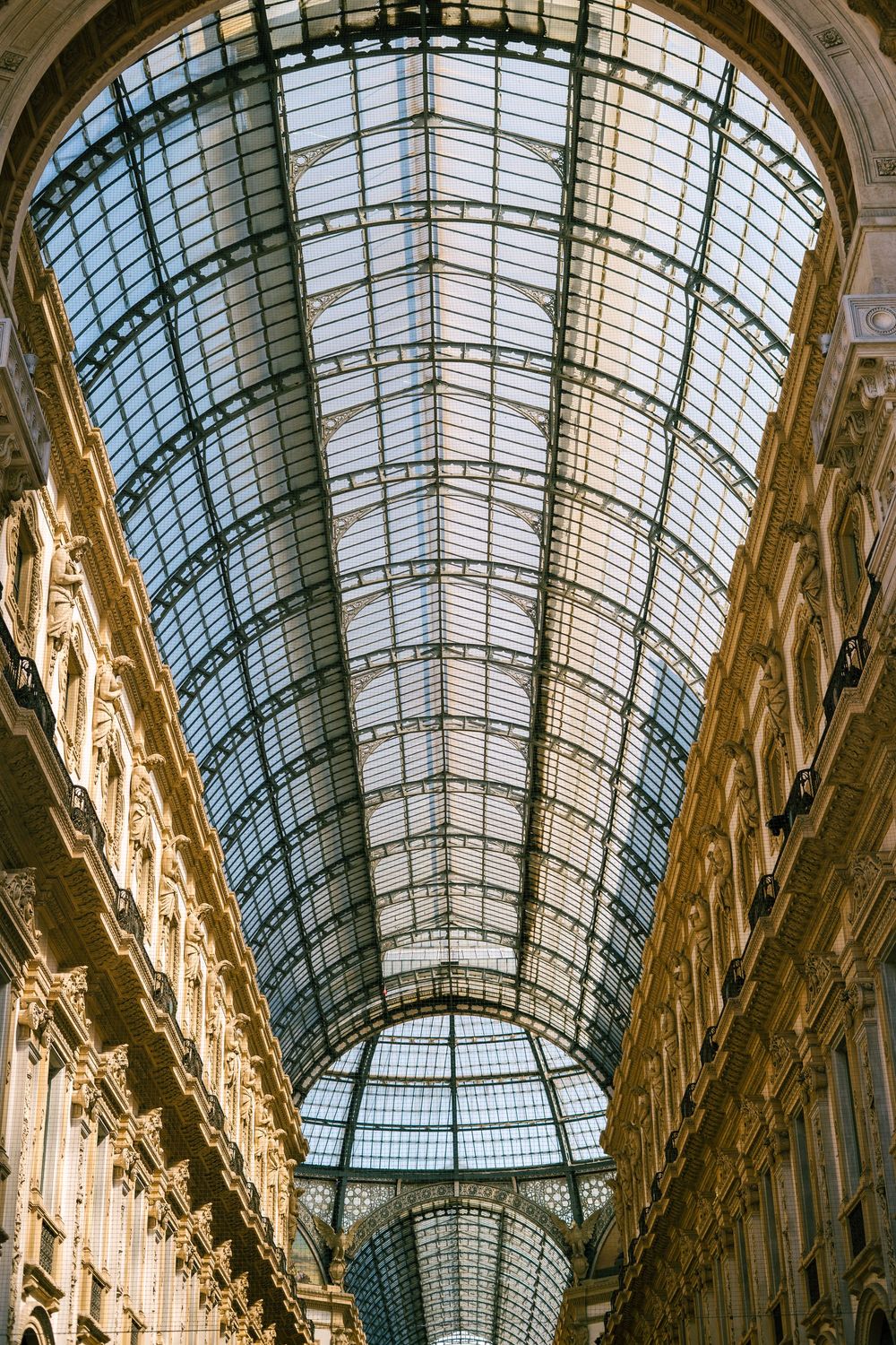 Ornate glass ceiling architecture in a historic European shopping gallery with natural light.