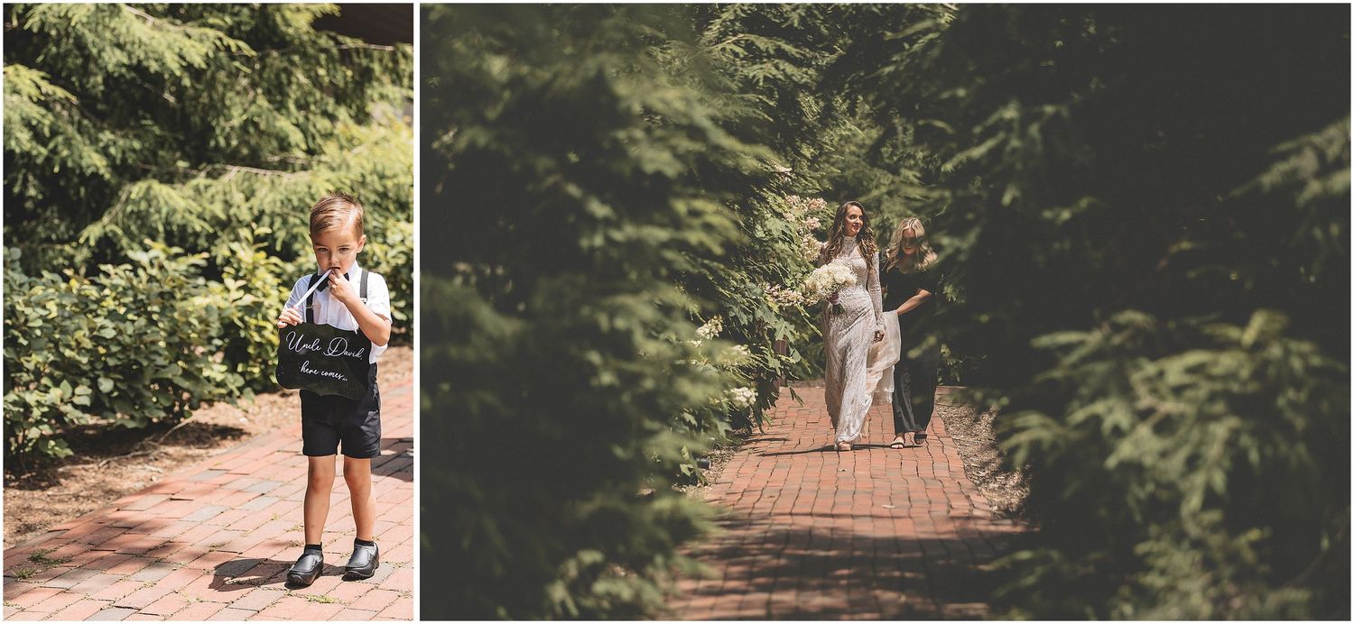 A couple walks hand in hand down a wooded path surrounded by lush green foliage at golden hour.