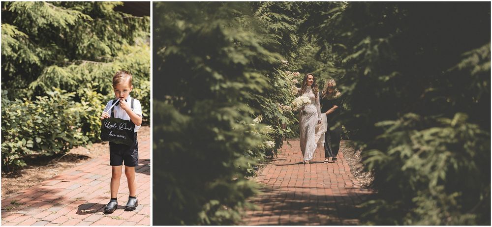 A couple walks hand in hand down a wooded path surrounded by lush green foliage at golden hour.